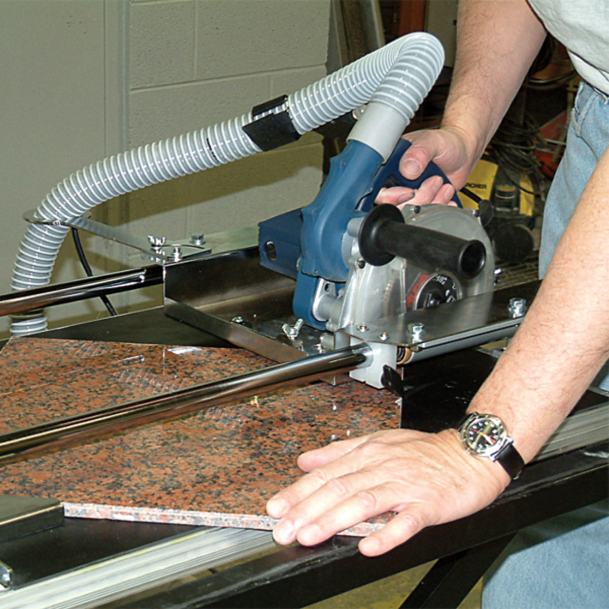 Person using the ecc-kit to cut through a slab of granite with a vacuum hose attached.