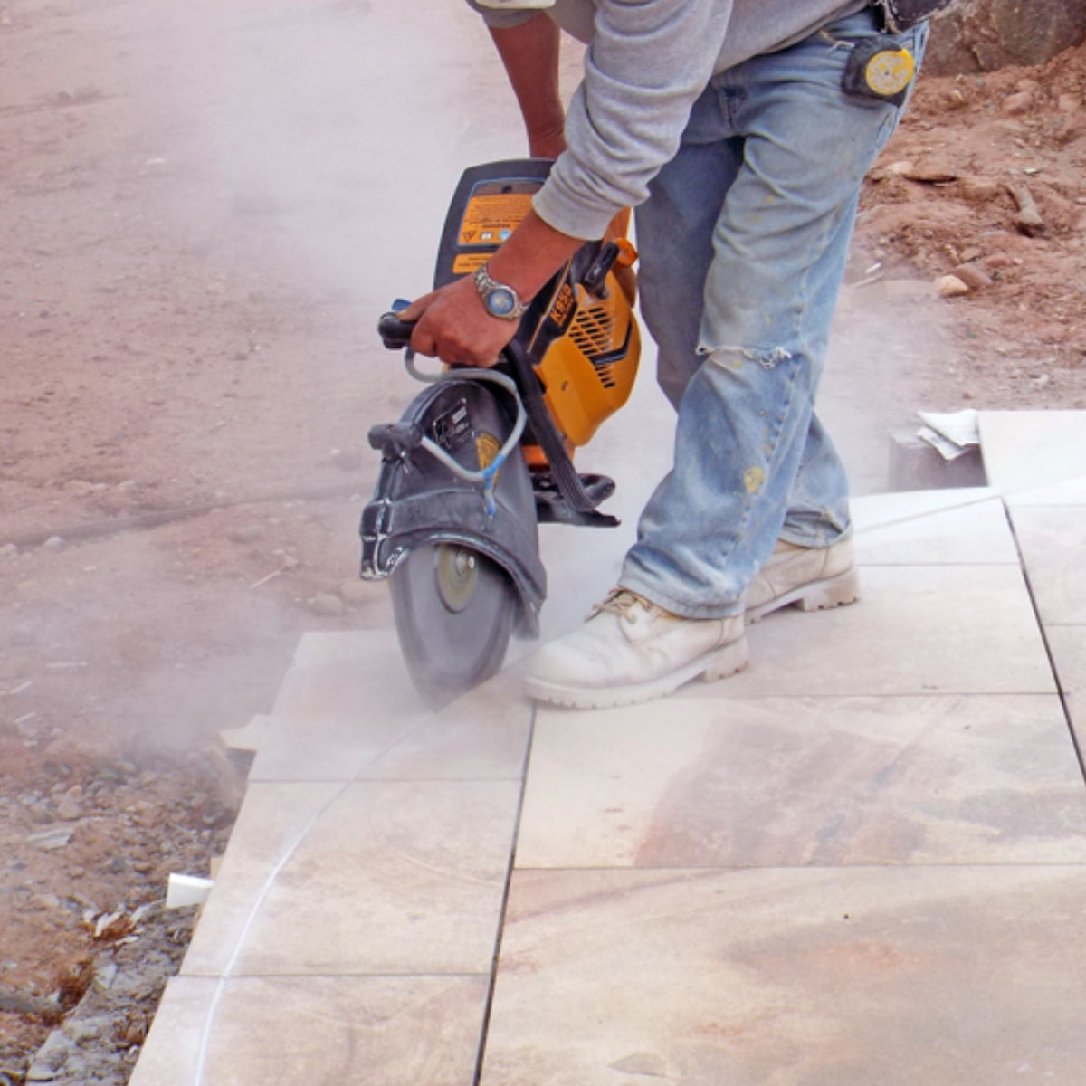 Person using a demolition saw with the Alpha PT Cutter diamond blade cutting porcelain pavers