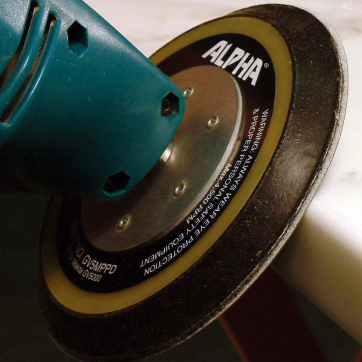Close-up of a sander with an Alpha brand sanding disc polishing a surface