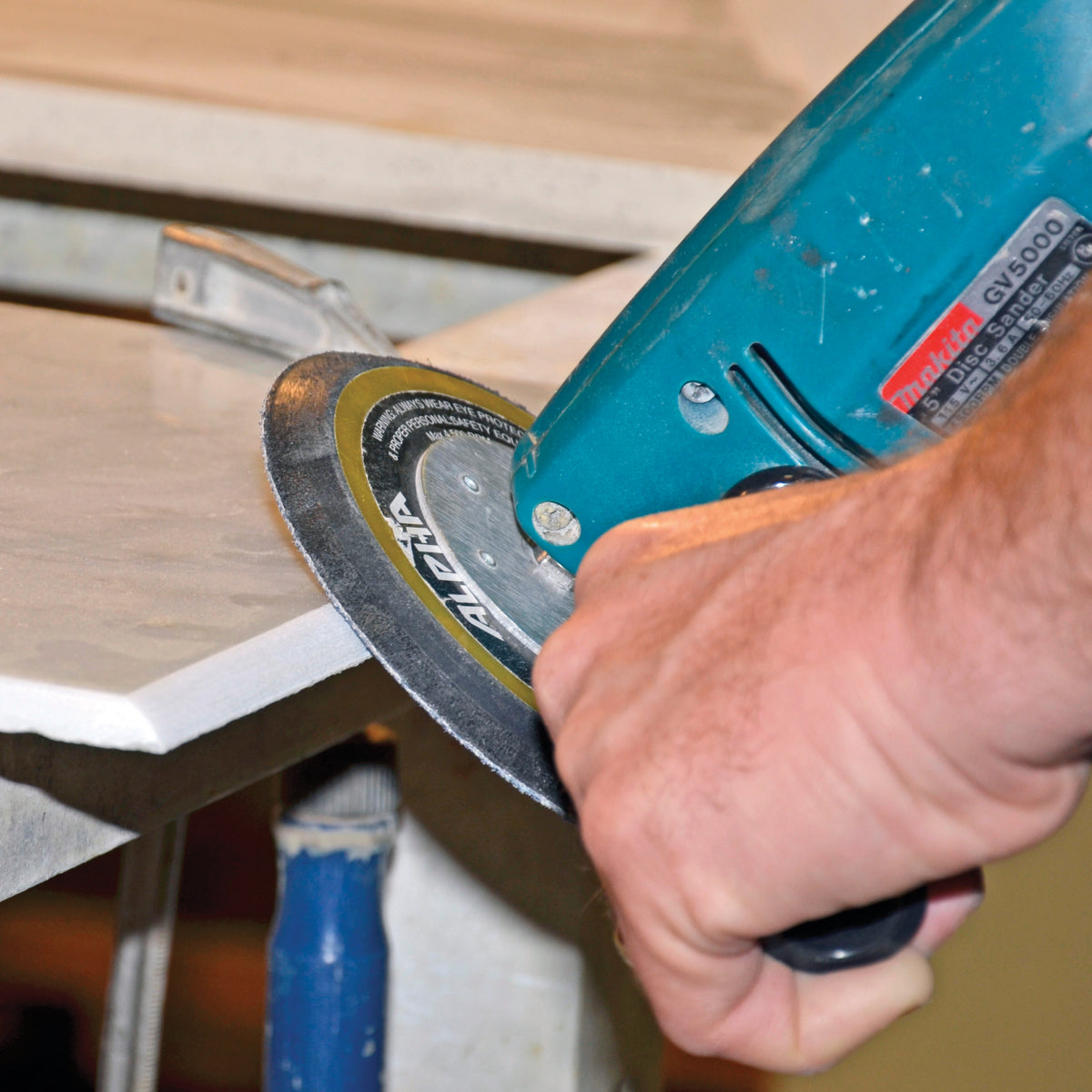 Person sanding a stone edge with  a Alpha sandpaper disc