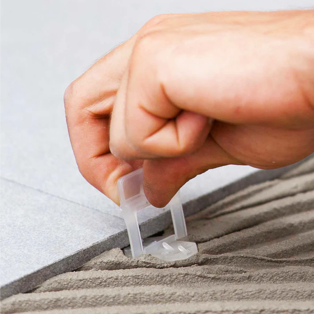 Raimondi 1/32" (1MM) Tile Leveling Clip Being Placed Under Porcelain Tile.